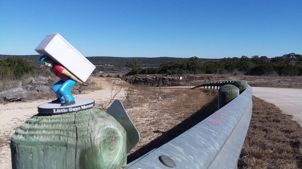 san marcos long distance moving Little Guys mascot in front of road