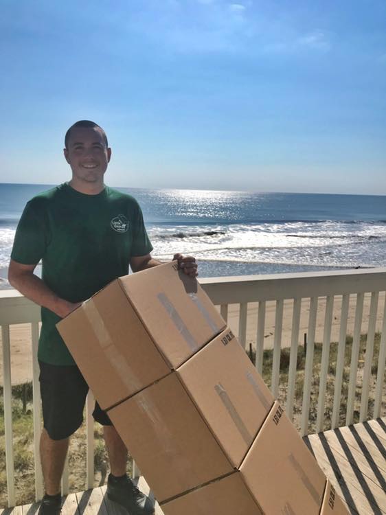 long distance movers holding boxes in front of ocean