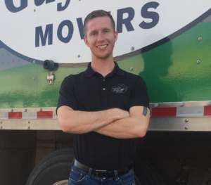 Lubbock Branch Manager Drew Brannon smiles in front of a Little Guys Movers moving truck.
