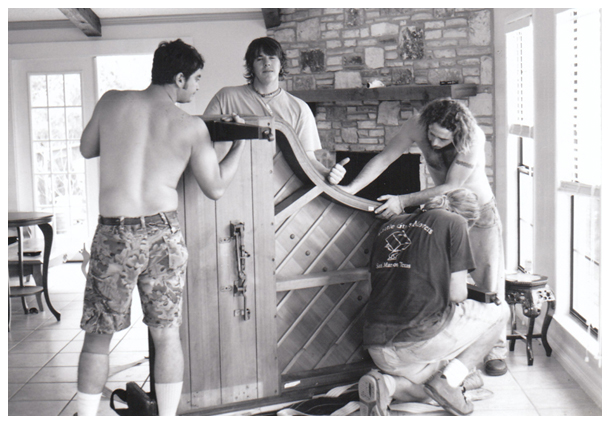 a black and white photo of four Little Guys carefully taking apart a customer's beautiful piano in preparation for the move